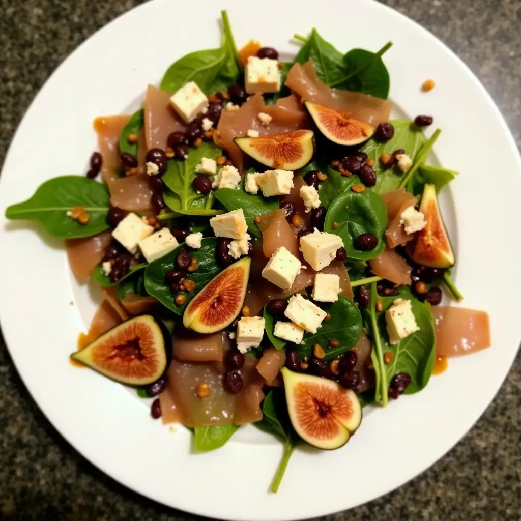 a photo of a Greek salad with figs, prosciutto, and a balsamic-fig dressing.